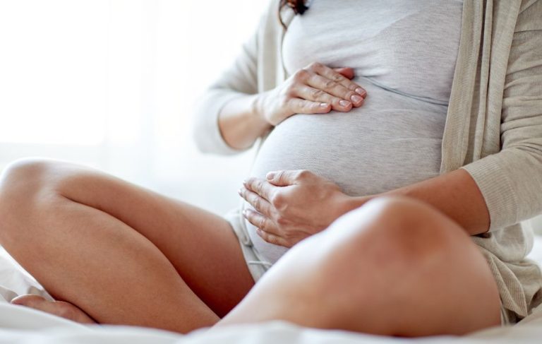 Pregnancy Must-Haves - Pregnant woman sitting and holding her belly